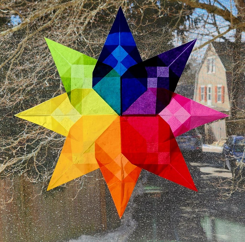Colorful, translucent folded paper stars on a window.