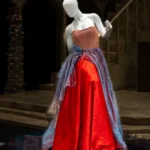 Mannequin wearing blue and red gown with pleated iridescent fabric