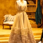 A grey gown with ruffles on a dress form.