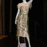 Mannequin wearing 3/4 length dress with layers of embridered and beaded leaves.