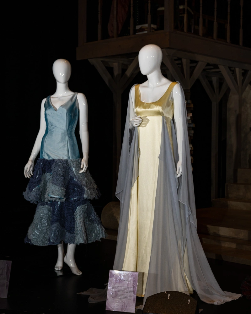 Two mannequins wearing gowns: on left, an ocean blue gown; on right, a gold and blue gown.