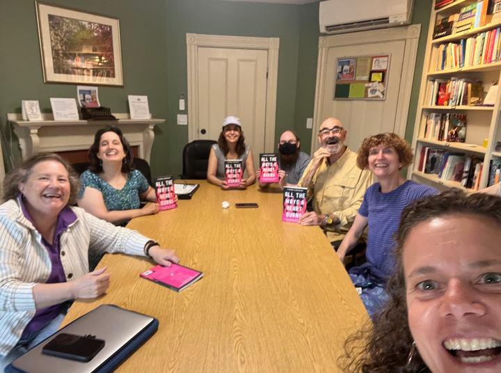 StoryClub2024 Smiling people gathered around a table with books