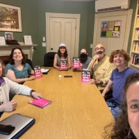 StoryClub2024 Smiling people gathered around a table with books