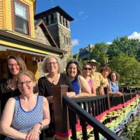 WritersinResBigYellow2024 (1) Eight writers-in-residence pose in front of Follow Your Art